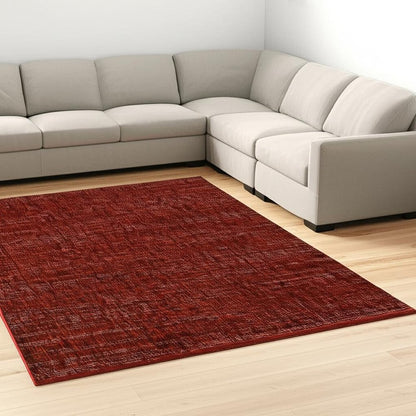 L-shaped beige fabric sectional surrounding a textured burgundy area rug on a light wooden floor.