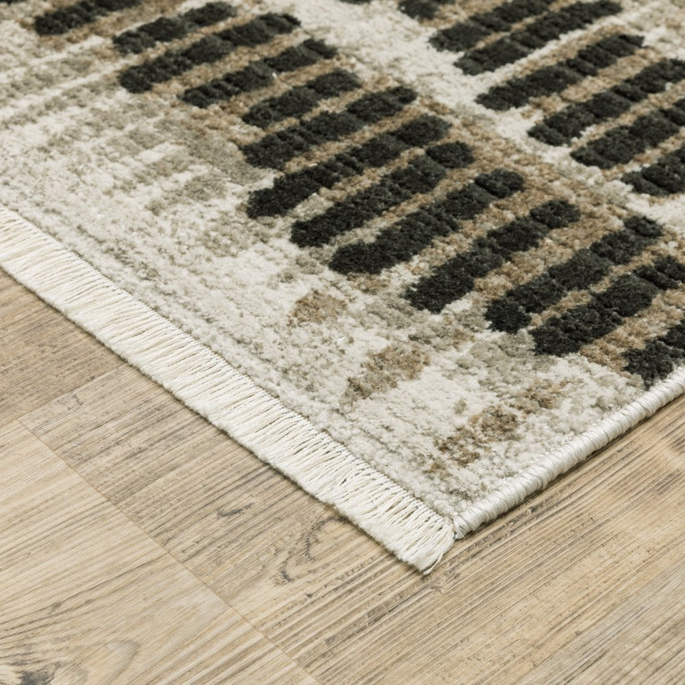 4' x 6' beige, ivory, charcoal, brown, tan and grey abstract area rug with fringe.