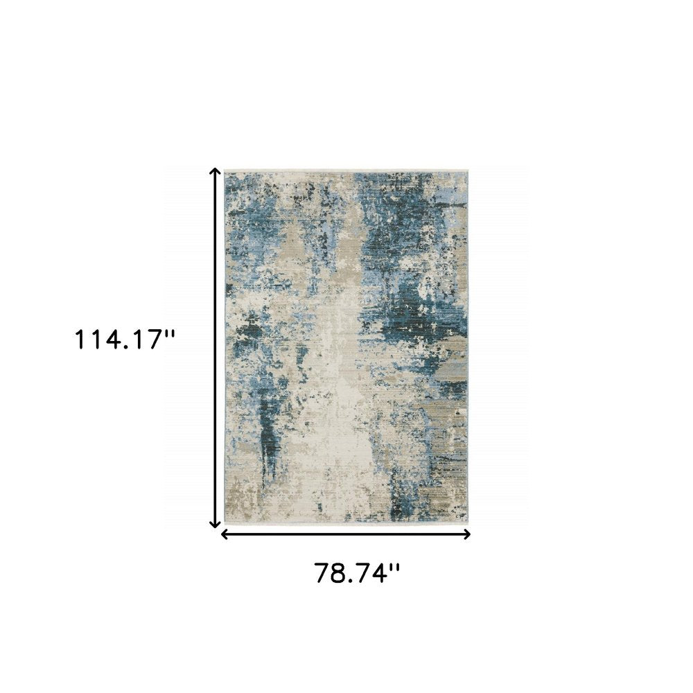 6' x 9' abstract area rug in blue, grey, ivory, light blue and dark blue with fringe; power loom; stain resistant.