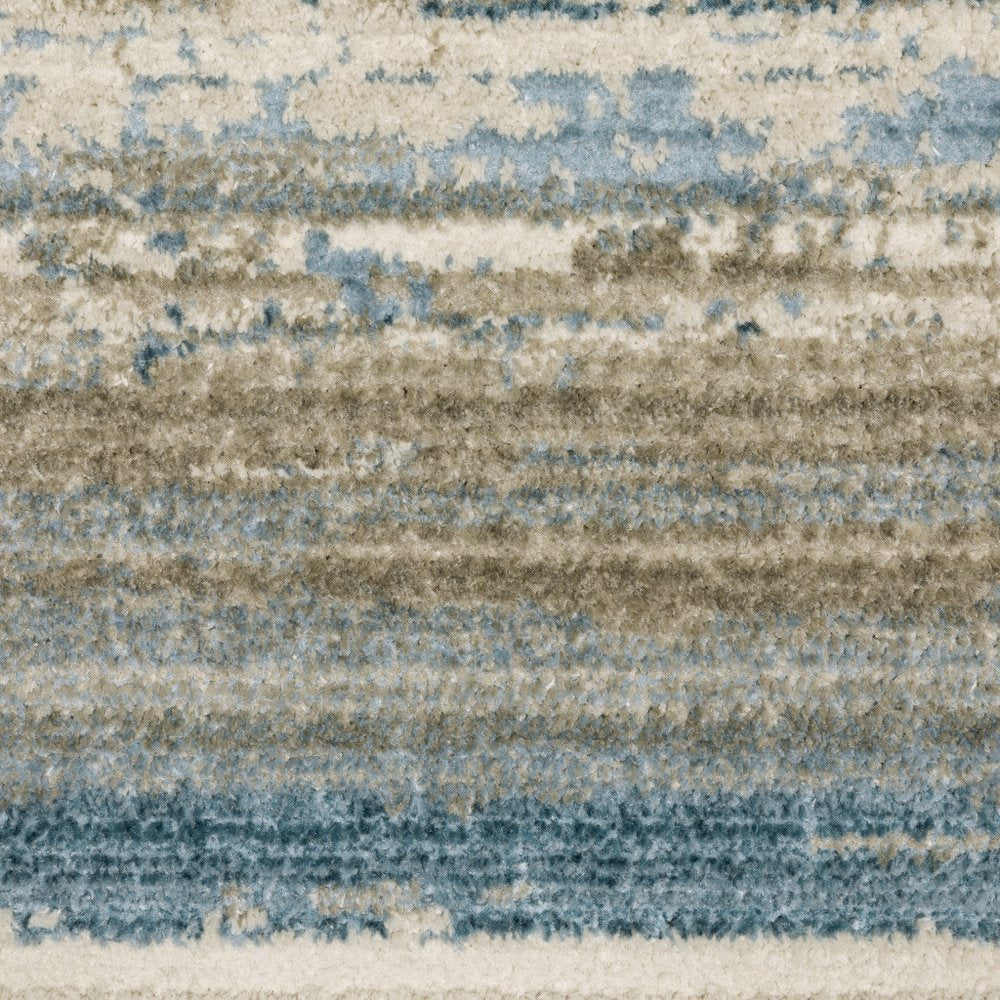 5' X 8' Ivory Beige Grey Blue And Tan Abstract Power Loom Stain Resistant Area Rug With Fringe
