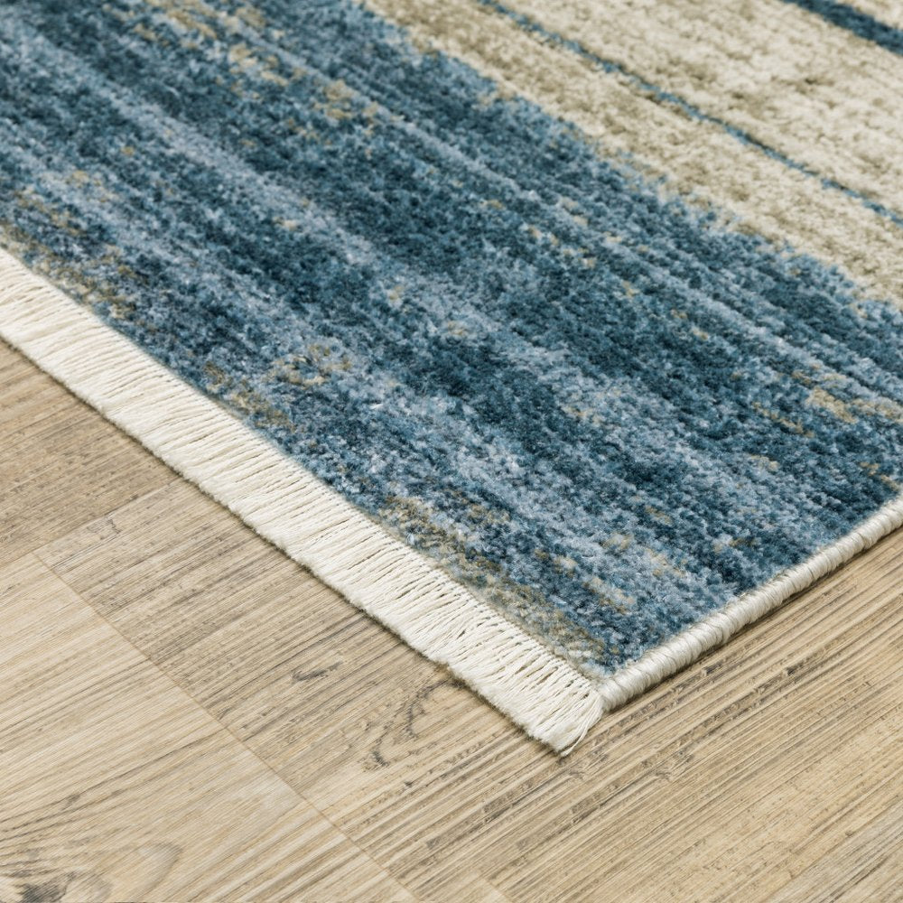 5' X 8' blue, dark blue, teal, grey, ivory, beige and tan geometric power loom stain resistant area rug with fringe