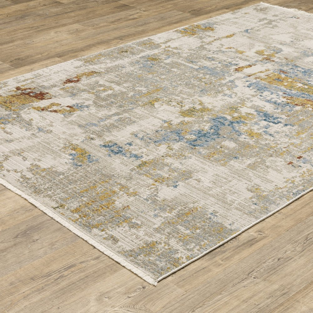6' x 9' abstract power loom stain-resistant area rug in beige, grey, gold, blue, rust and teal with fringe