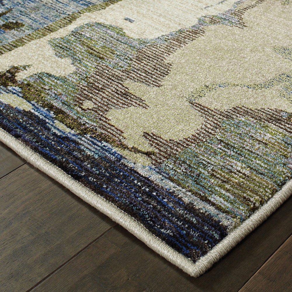Abstract blue and gray runner rug with cream and tan accents; beige binding edge on dark wood floor.