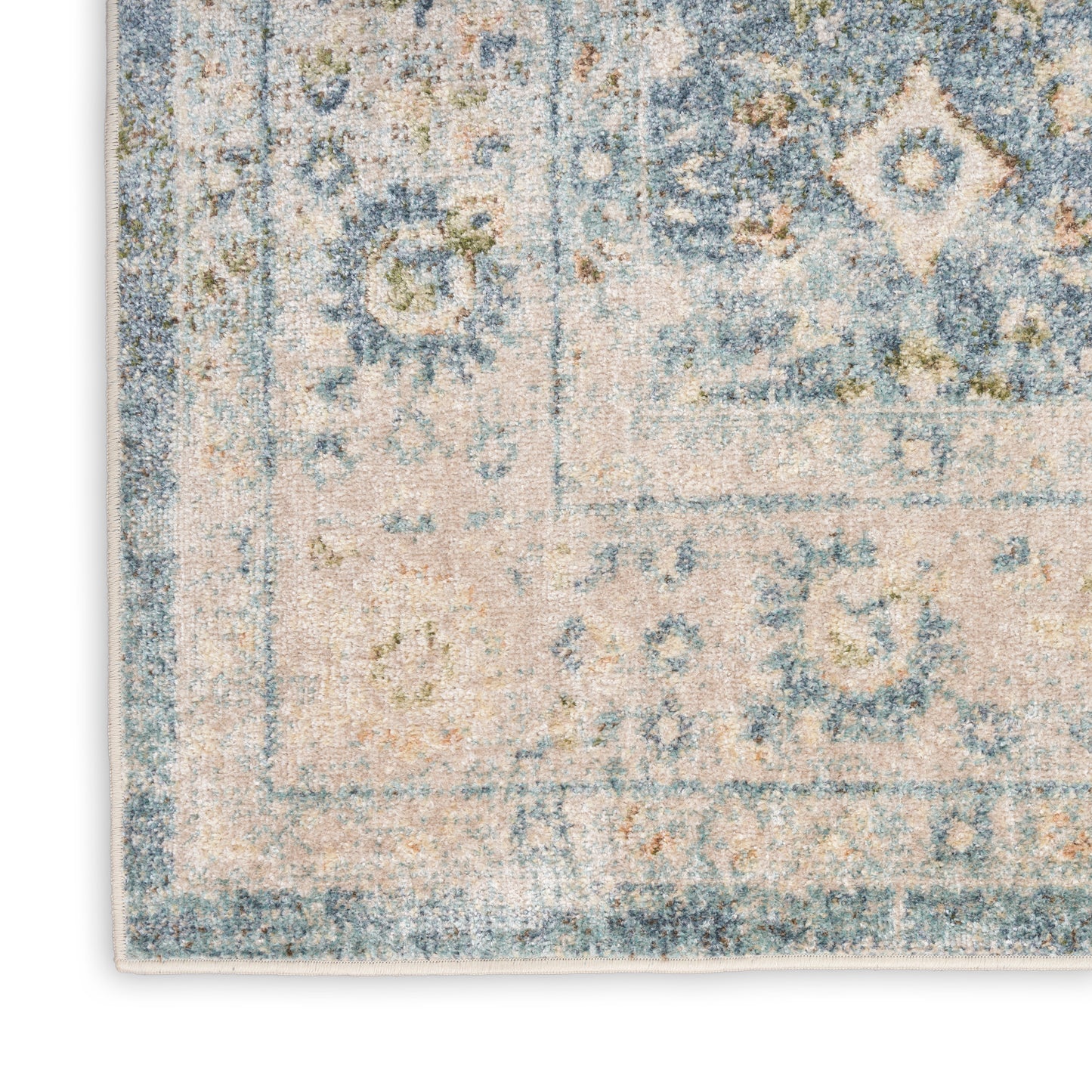 Blue and cream distressed oriental rug corner with geometric medallions and a faded border.