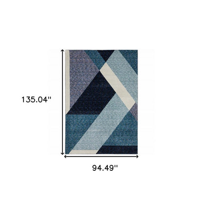 Rectangular geometric area rug in blues, navy, gray and cream with overlapping angular blocks.