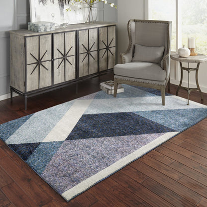 Geometric blue-gray area rug on dark hardwood floor beside a weathered wood sideboard and gray upholstered armchair.
