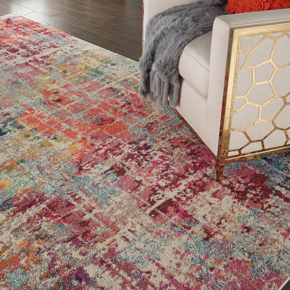 Colorful distressed area rug with abstract floral pattern in reds, blues, yellows; beige sofa with gold honeycomb side table.