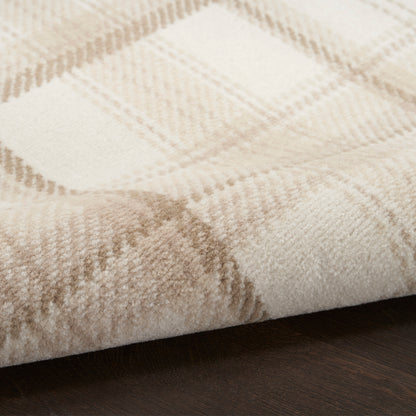 Cream and beige plaid rug with soft, fuzzy pile; close-up view on dark wood floor.