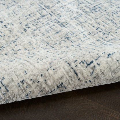 Cream and blue distressed modern area rug with plush pile on dark wood floor.