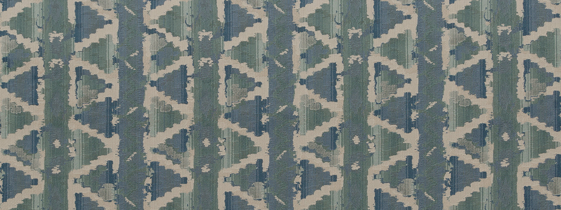 Teal and blue ikat-style geometric upholstery fabric with repeating triangles and diamonds on an off-white background.