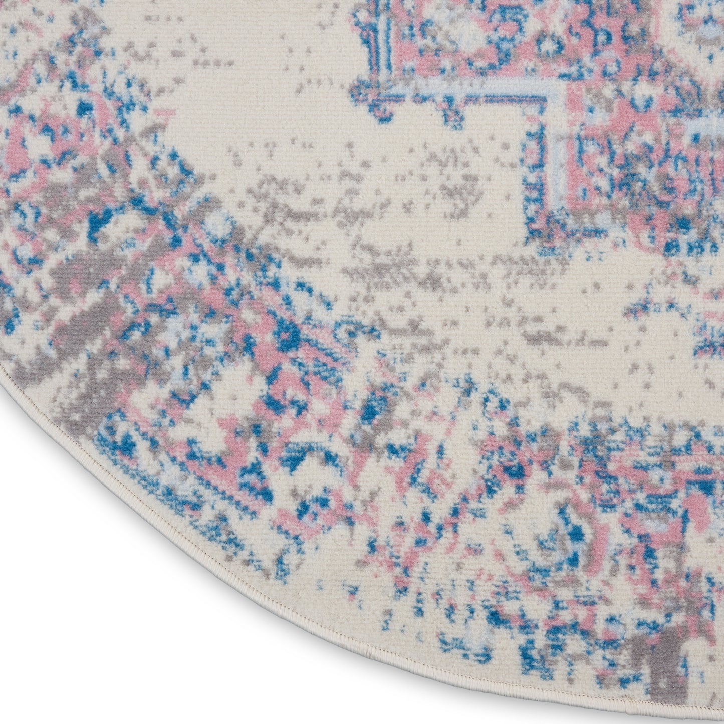 Round cream rug with distressed pink, blue and gray floral pattern.