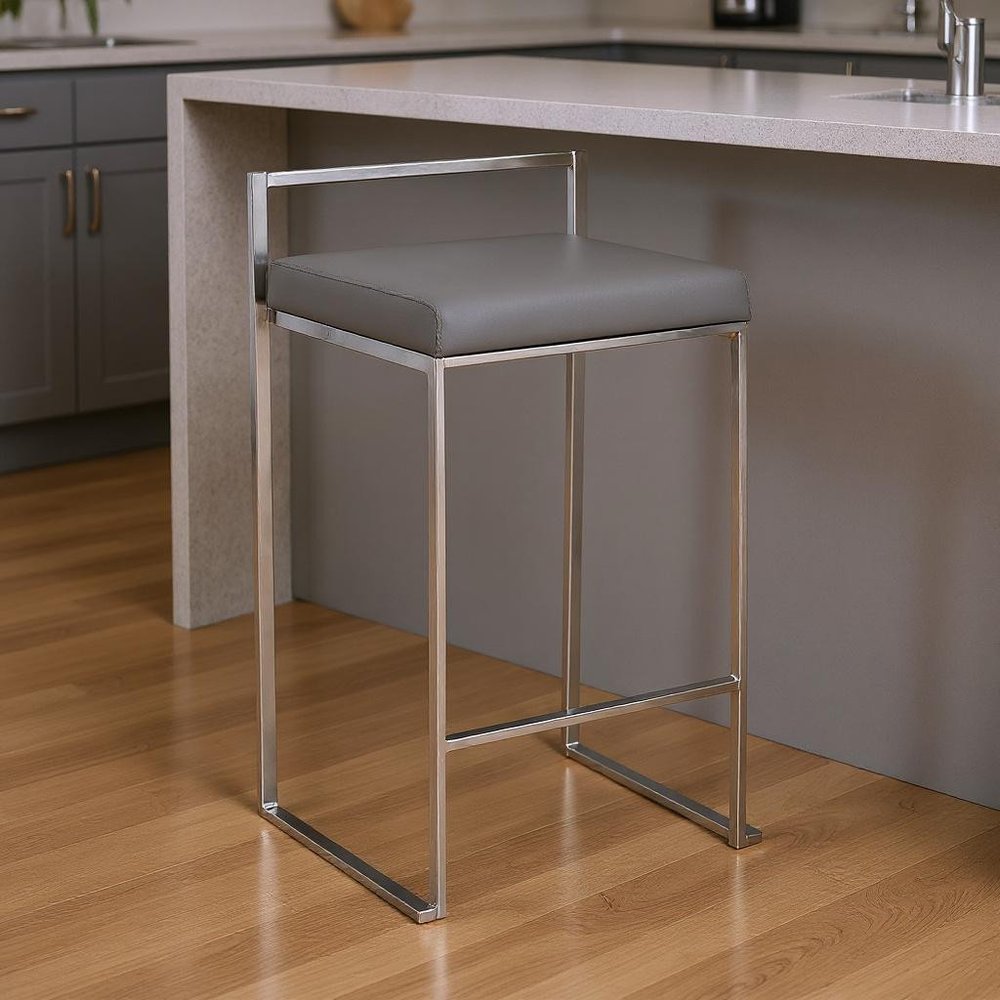 Chrome bar stool with gray padded seat, backless, under modern kitchen island; industrial metal frame, counter-height.