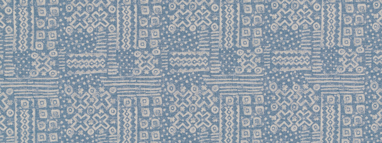 Blue denim woven fabric with white geometric ikat-inspired motifs in a repeating grid pattern.