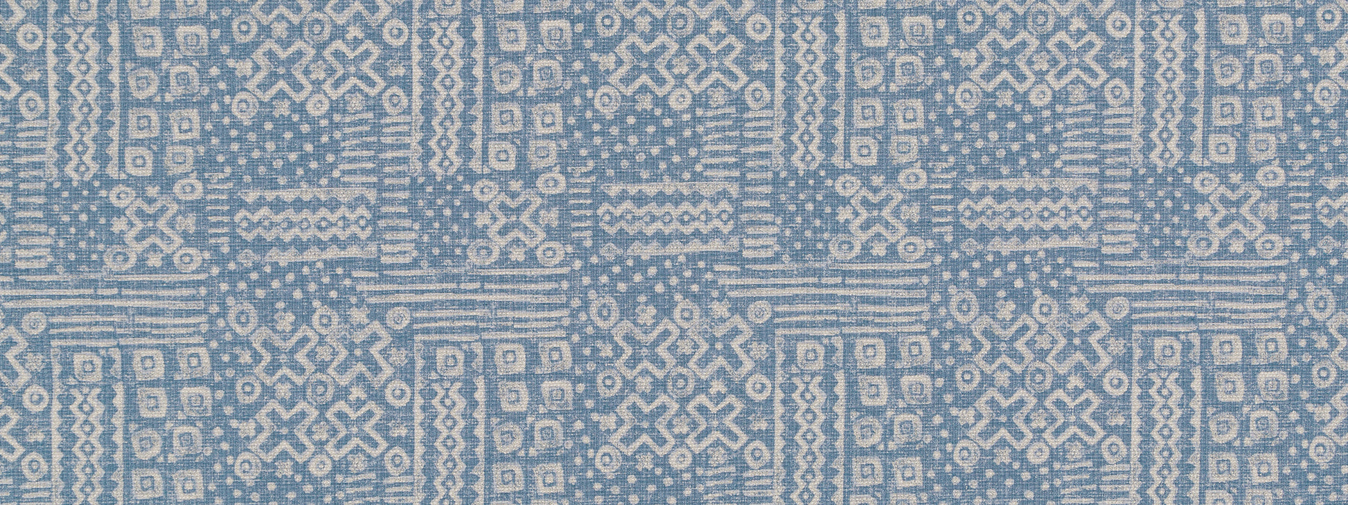 Blue denim woven fabric with white geometric ikat-inspired motifs in a repeating grid pattern.