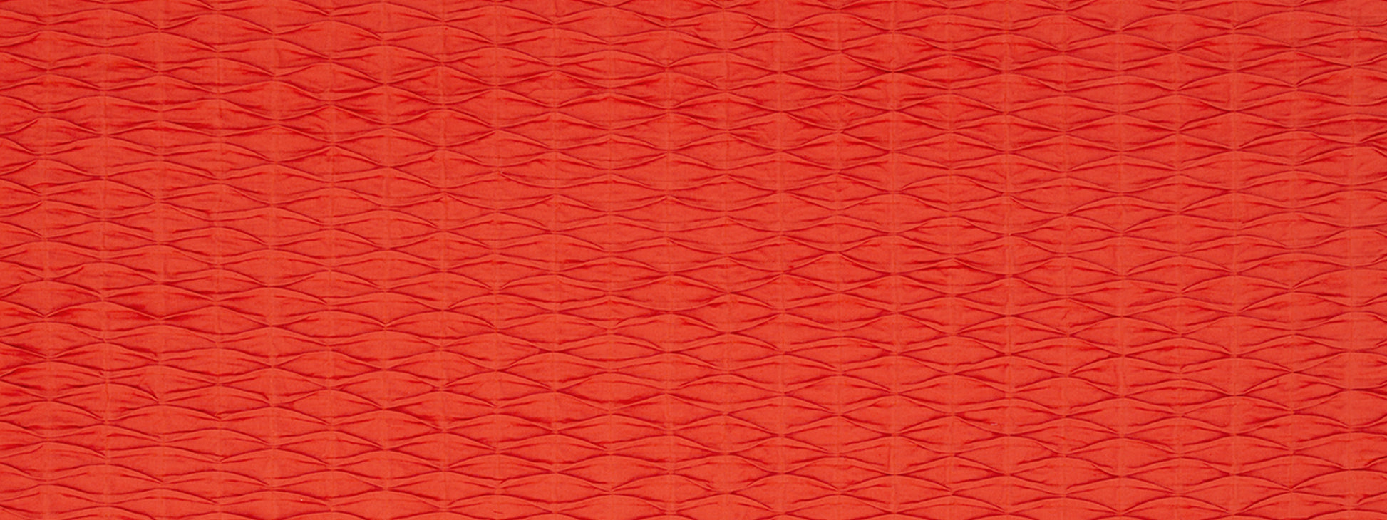 Red textured fabric with a small repeating diamond weave pattern; warm, vibrant upholstery material.