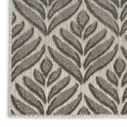 Rectangular beige outdoor runner rug with dark taupe leafy pattern, woven textured surface, bound edge, modern botanical style.