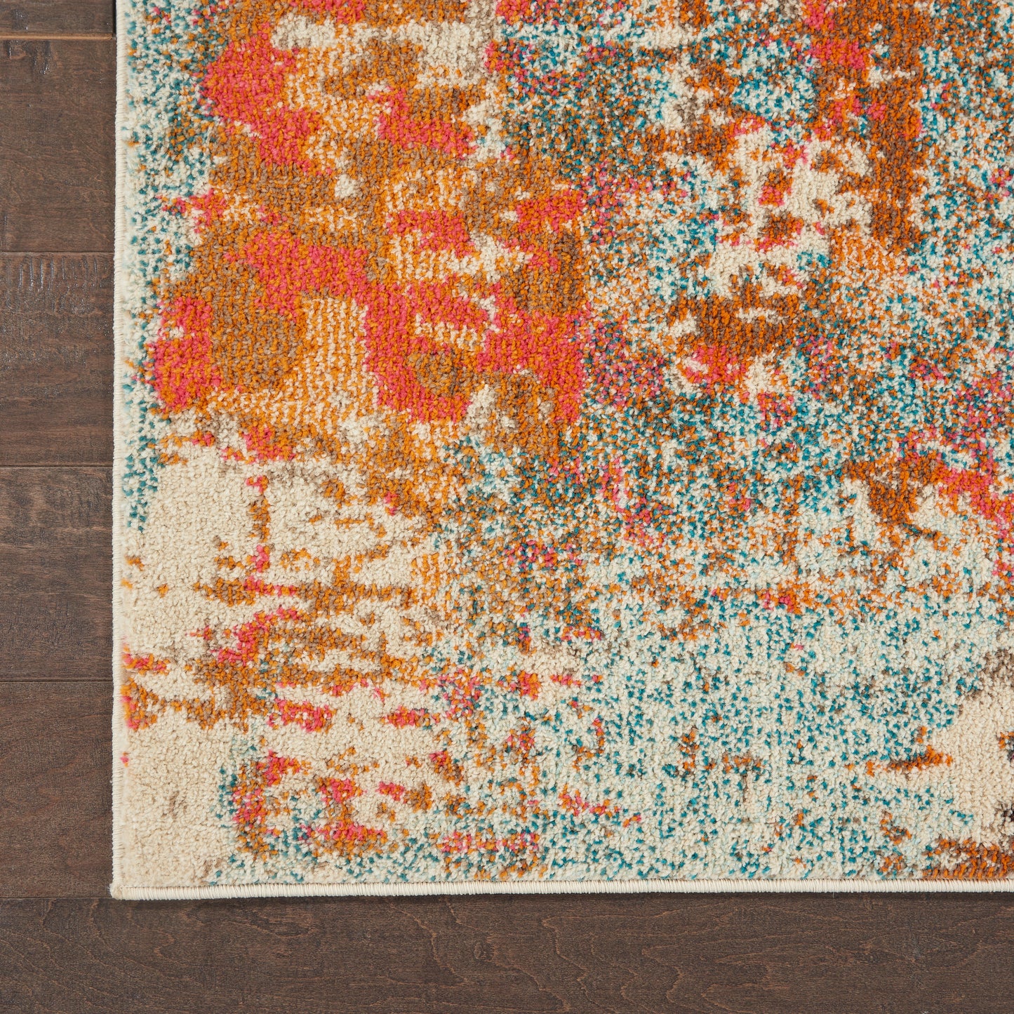 Abstract area rug with teal, orange, pink and cream patches; plush shag-like pile and beige border on wood floor.