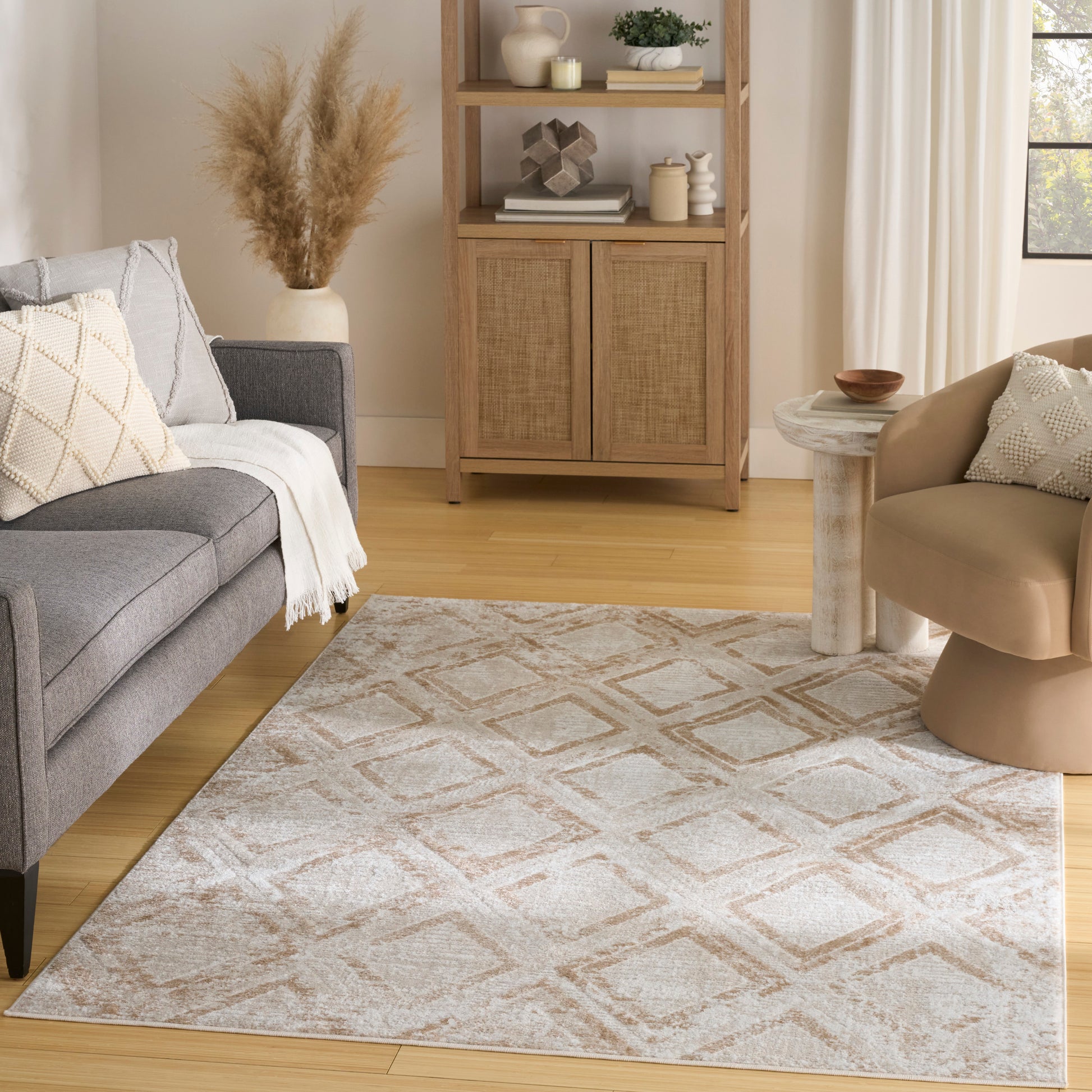 Neutral living room with gray sofa, cream throw, beige rug, light wood floor, wicker cabinet, beige armchair & round table.