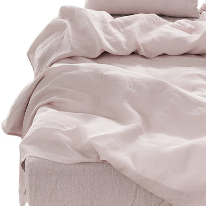 Light gray linen-look four-piece California King sheet set on a bed with wrinkled sheets and pillowcases.