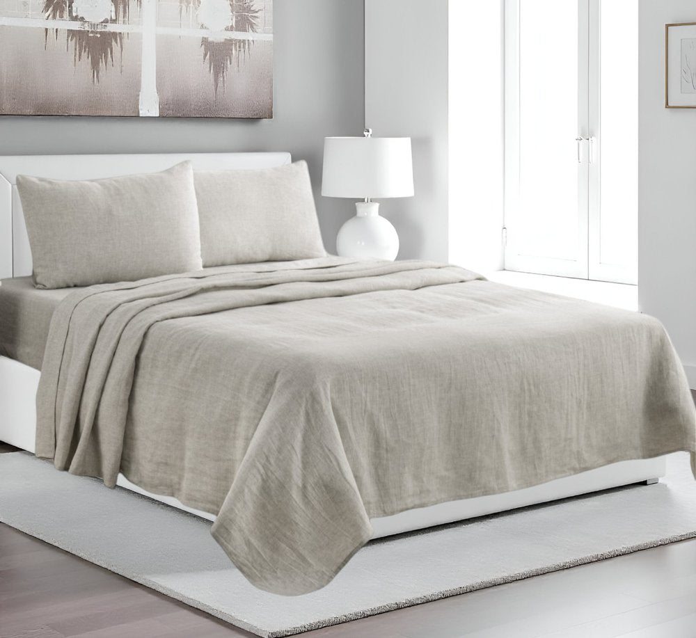 Light gray linen sheet set with matching pillowcases on a white platform bed in a neutral gray-walled bedroom with a white lamp.