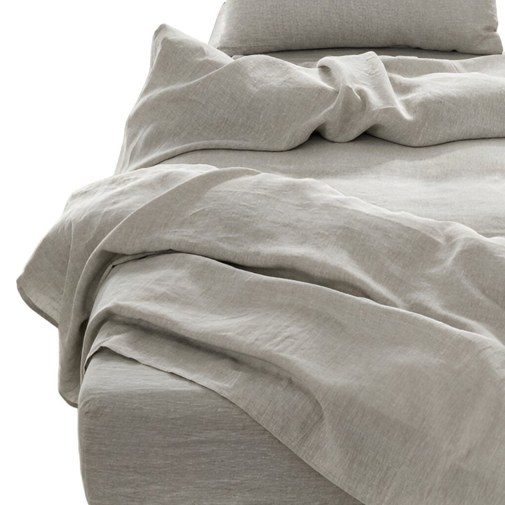 Light gray linen California King four-piece sheet set with matching pillowcases on a crumpled bed for a cozy minimalist look.