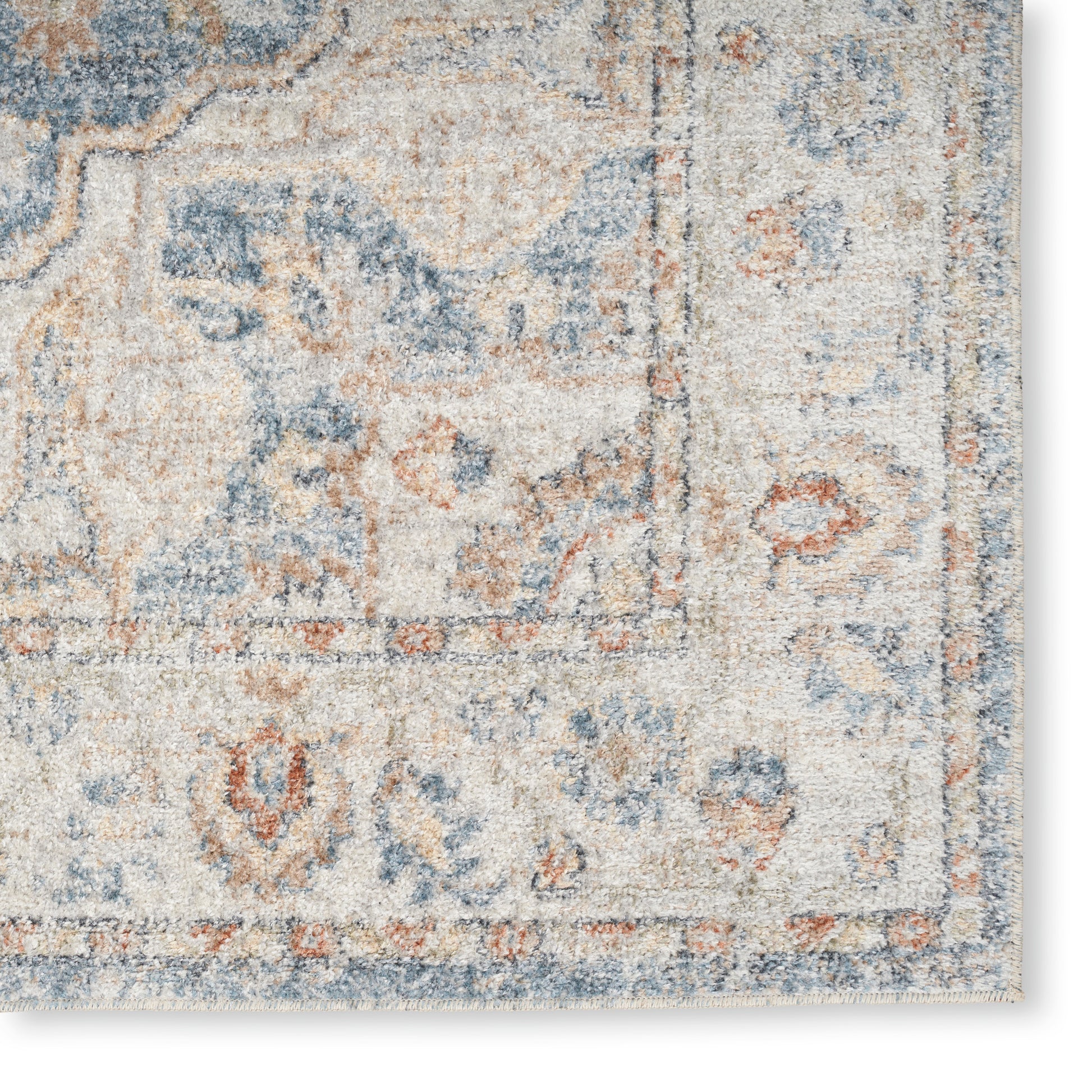 Rectangular vintage-style area rug in blue, cream and tan with distressed floral pattern and bordered edge, fringe trim.