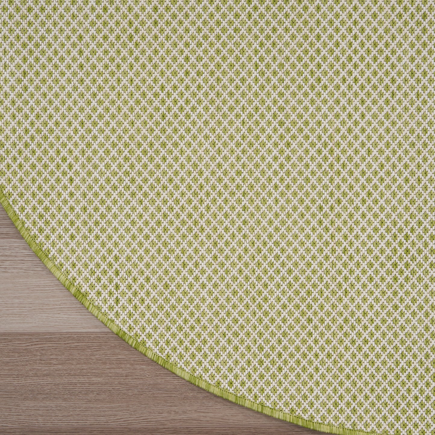 Round rug with lime-green and white lattice pattern, lime edge, on wooden floor.