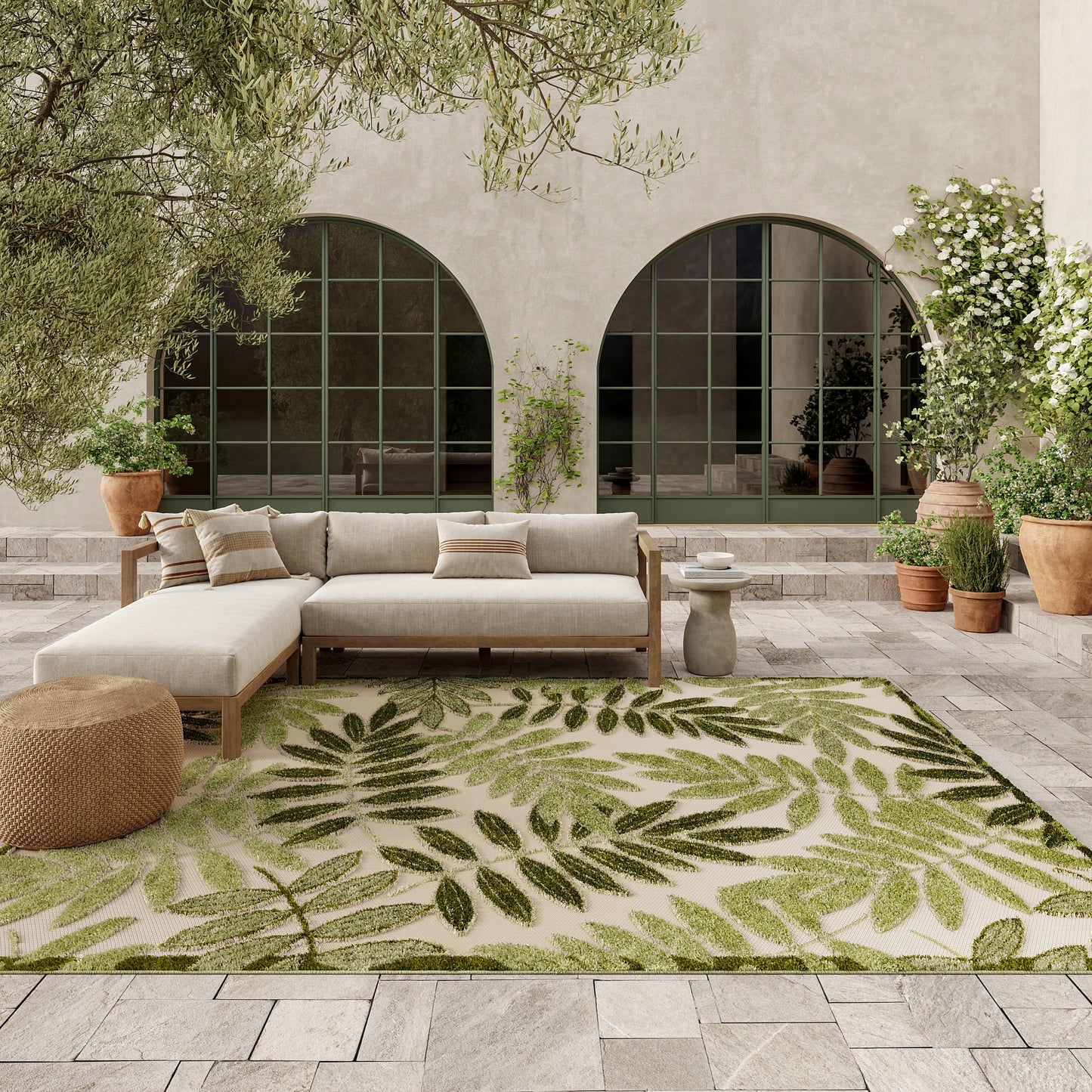 Outdoor palm-leaf rug on beige tile patio by arched glass doors with potted plants.