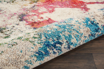 Colorful abstract shag area rug with beige base, blue/teal accents and pink highlights, partially rolled on dark wood floor.