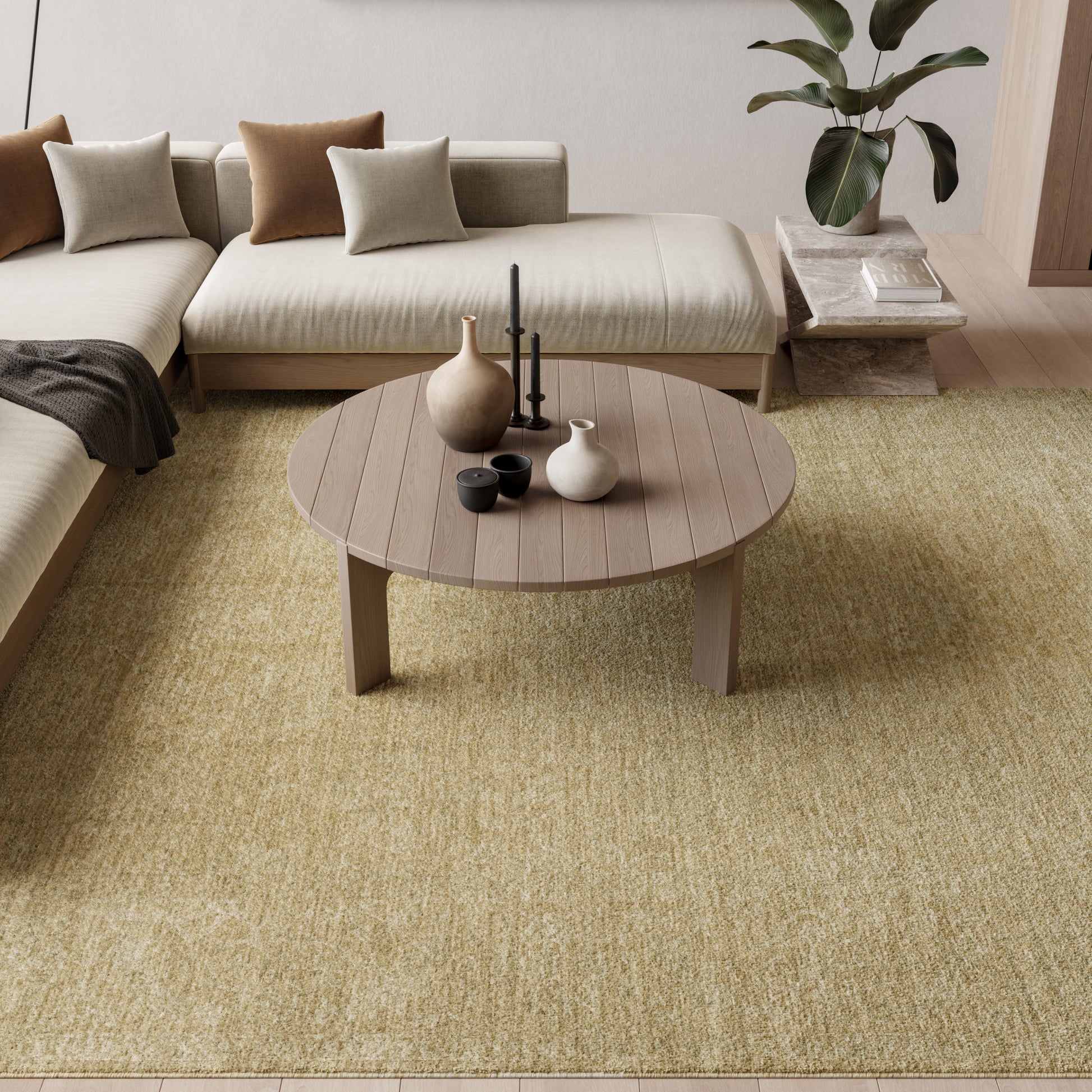 Round wooden coffee table on a yellow-beige rug, beige sectional with brown & taupe cushions, ceramic vases & candles.