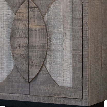 Graywashed wooden cabinet with carved leaf motif on panel doors; rustic farmhouse storage.