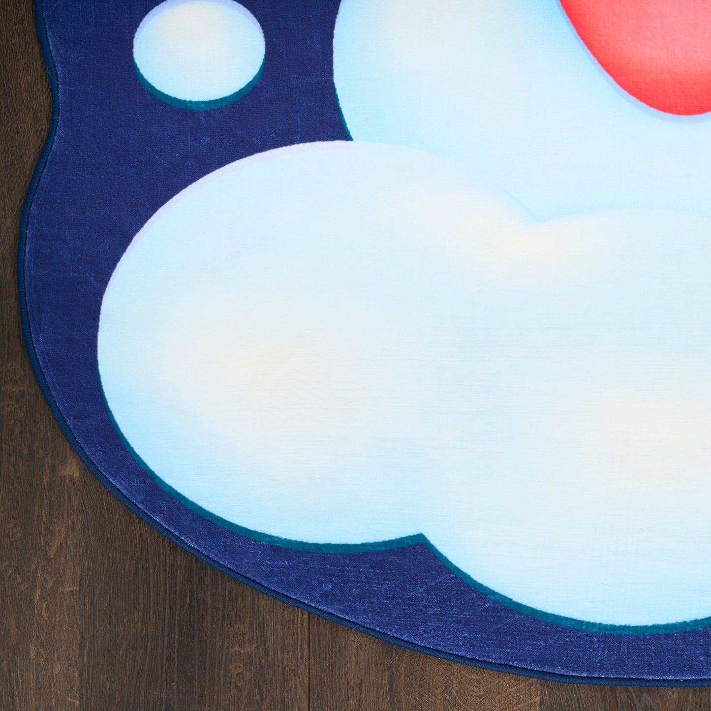 Round rug with navy border featuring pale blue clouds and teal edge on wooden floor.