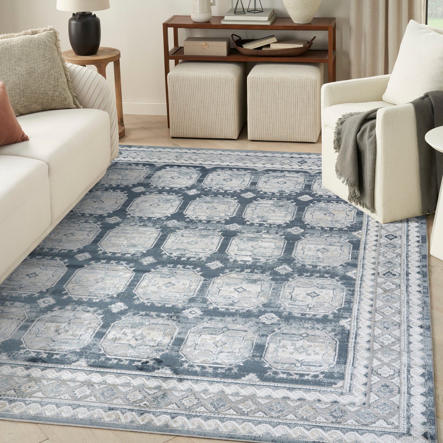 Blue-gray oriental style area rug with ivory medallions and geometric borders in a modern neutral living room.