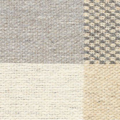 Patchwork rug with four textures: grey tweed, beige weave, cream knit stripes, and tan jute-like weave.