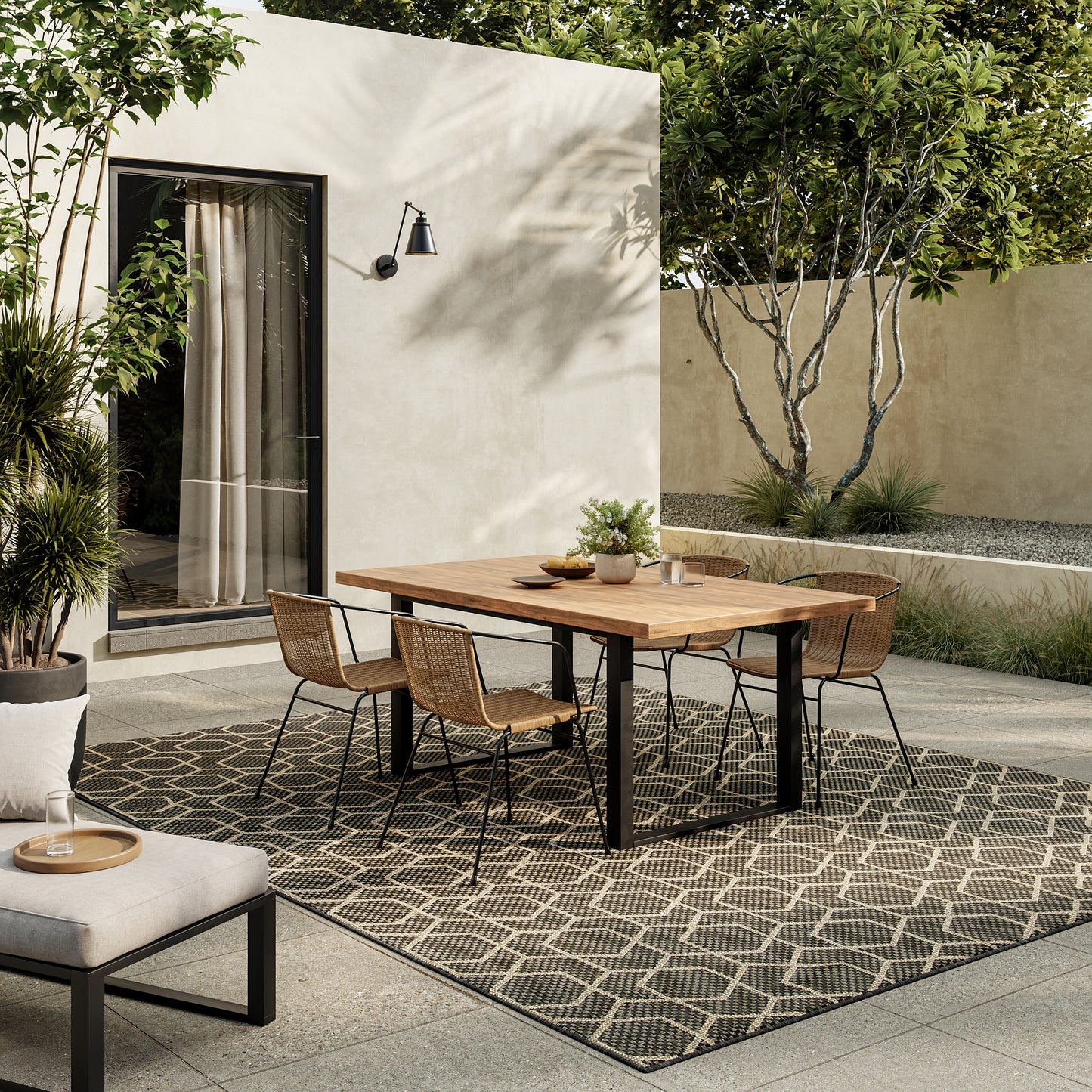 Outdoor dining set with rectangular wooden table, black metal legs, six wicker chairs on a geometric lattice rug.