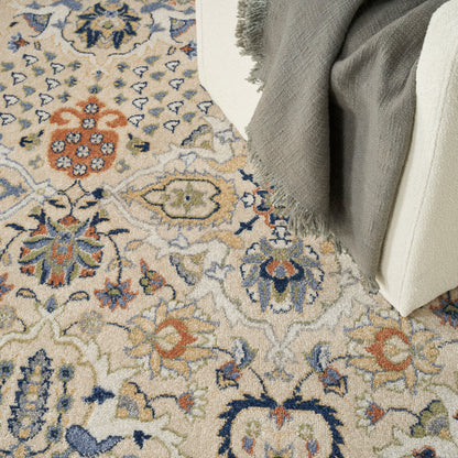 Beige oriental-style rug with blue, orange, and green floral medallions; gray fringed throw over cream furniture.
