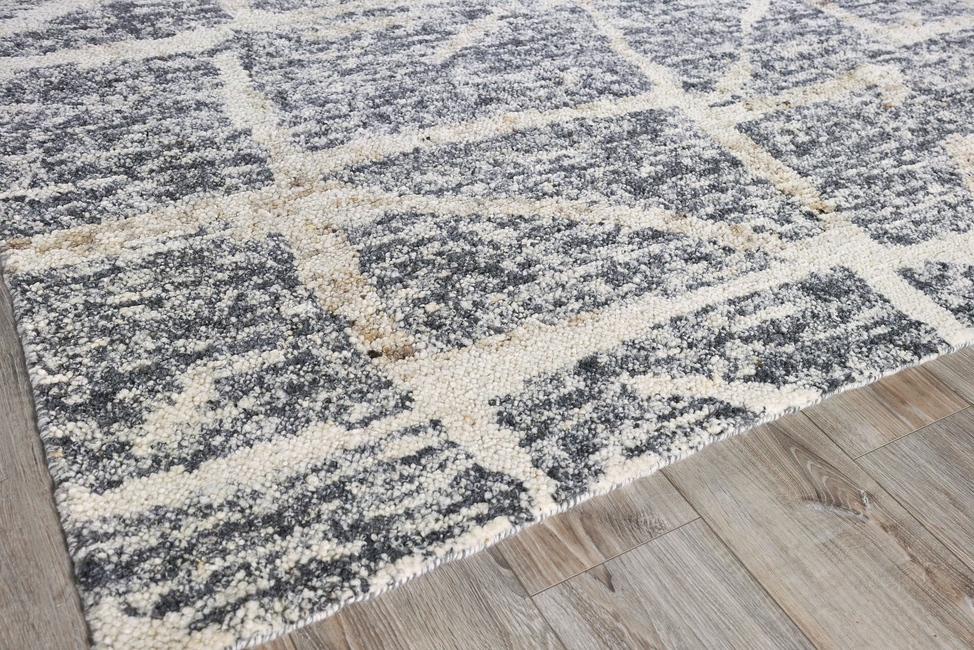 Charcoal gray and ivory hand-knotted rug with a large geometric grid pattern on wood floor