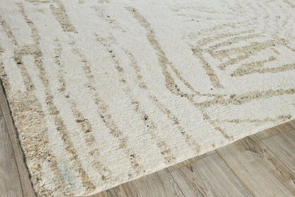 Cream and beige textured area rug with abstract linear pattern on light wood floor.