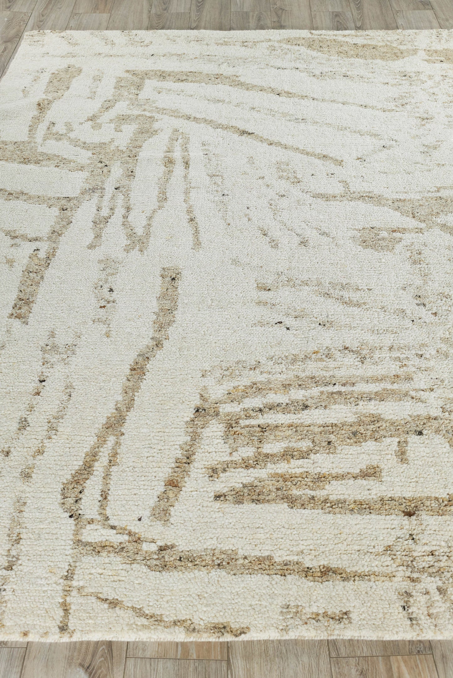 Rectangular beige indoor hand-knotted rug with abstract taupe lines, modern geometric pattern and soft textured pile.