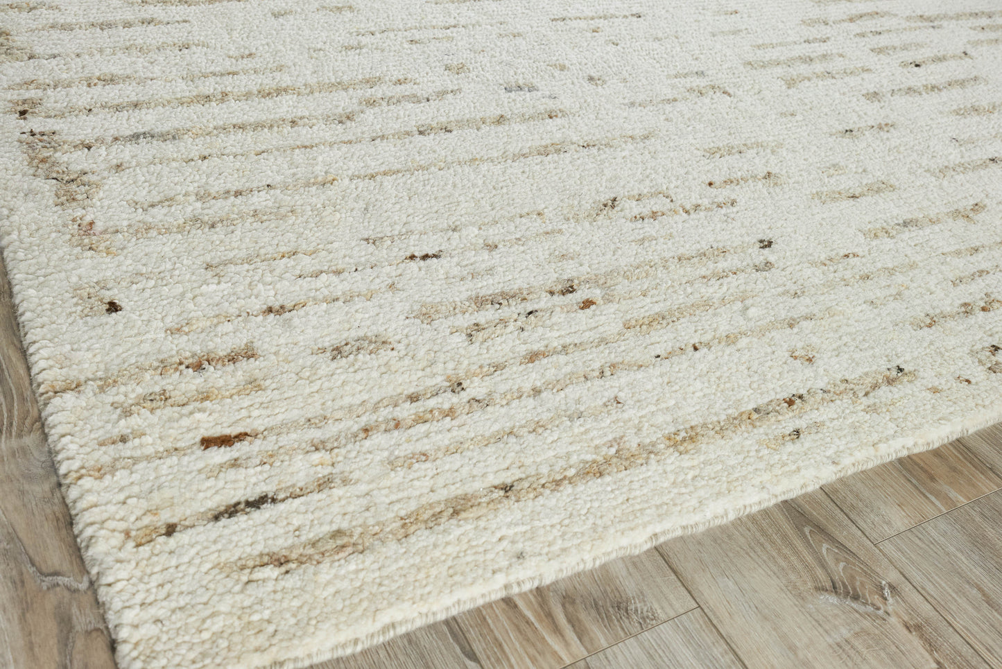 Rectangular cream hand-knotted rug with subtle brown flecks on a light wood floor.