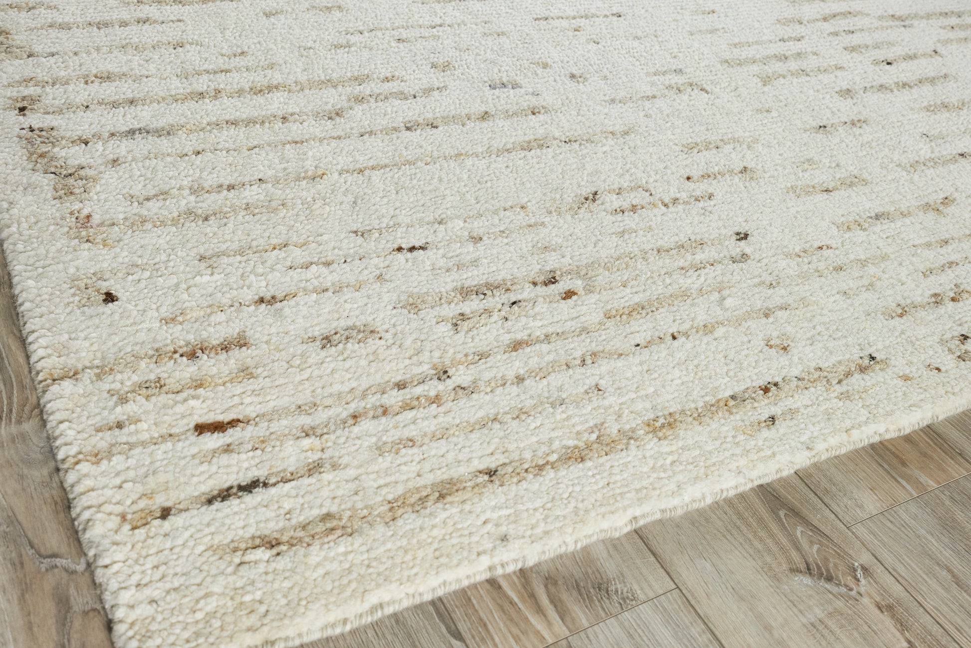 Rectangular cream hand-knotted rug with subtle brown flecks on a light wood floor.
