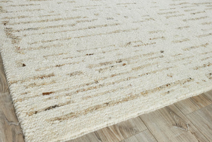 Rectangular cream hand-knotted rug with subtle brown flecks on a light wood floor.