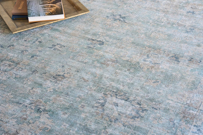 Blue-green distressed rug with faded floral pattern; wooden tray with books in top-left corner.