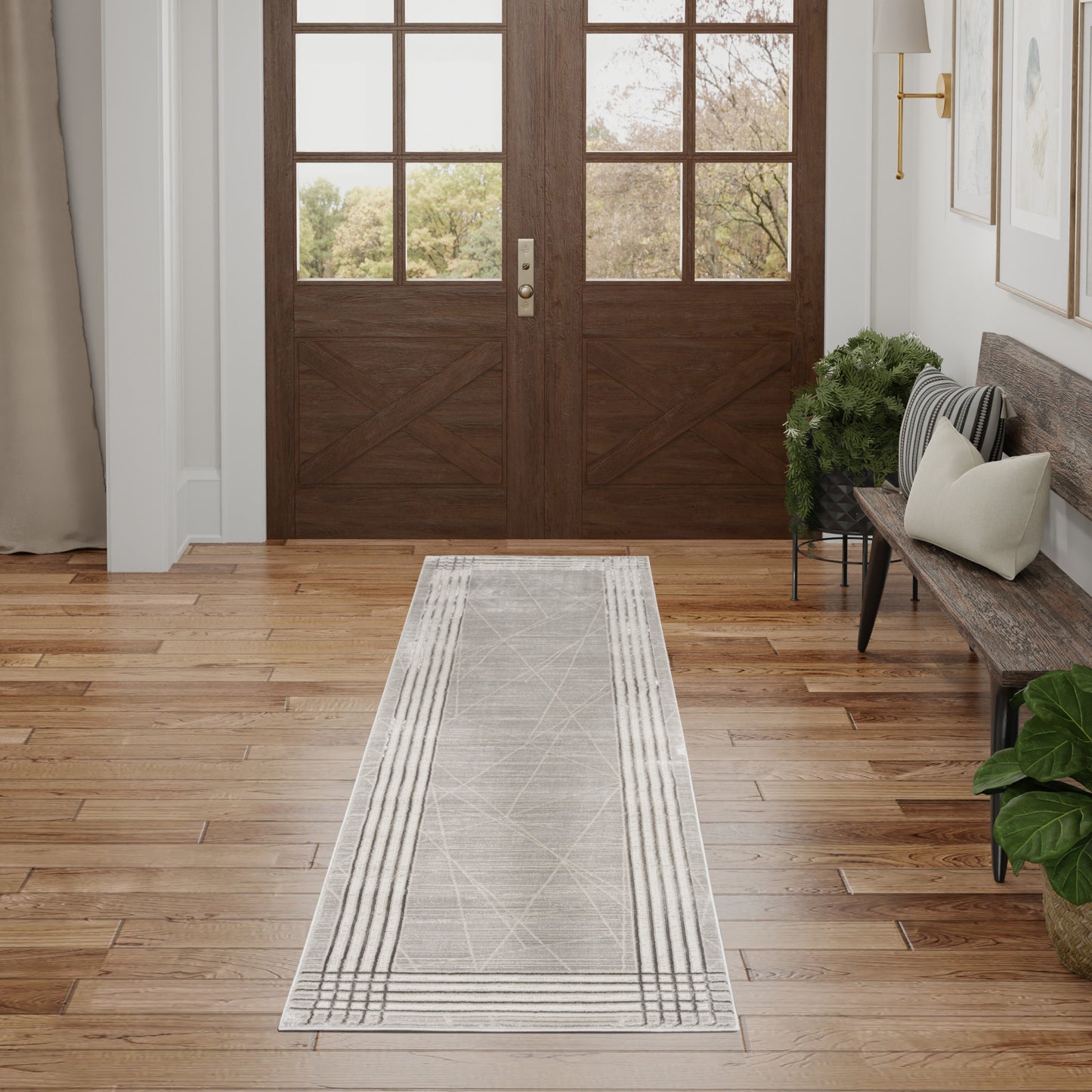 Cozy foyer with dark wood doors, glass panes, light floor, gray geometric runner rug, bench with cushions, plants.