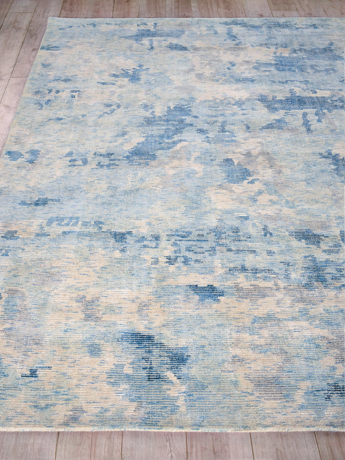 Abstract blue and ivory rug with distressed pattern on light wood floor