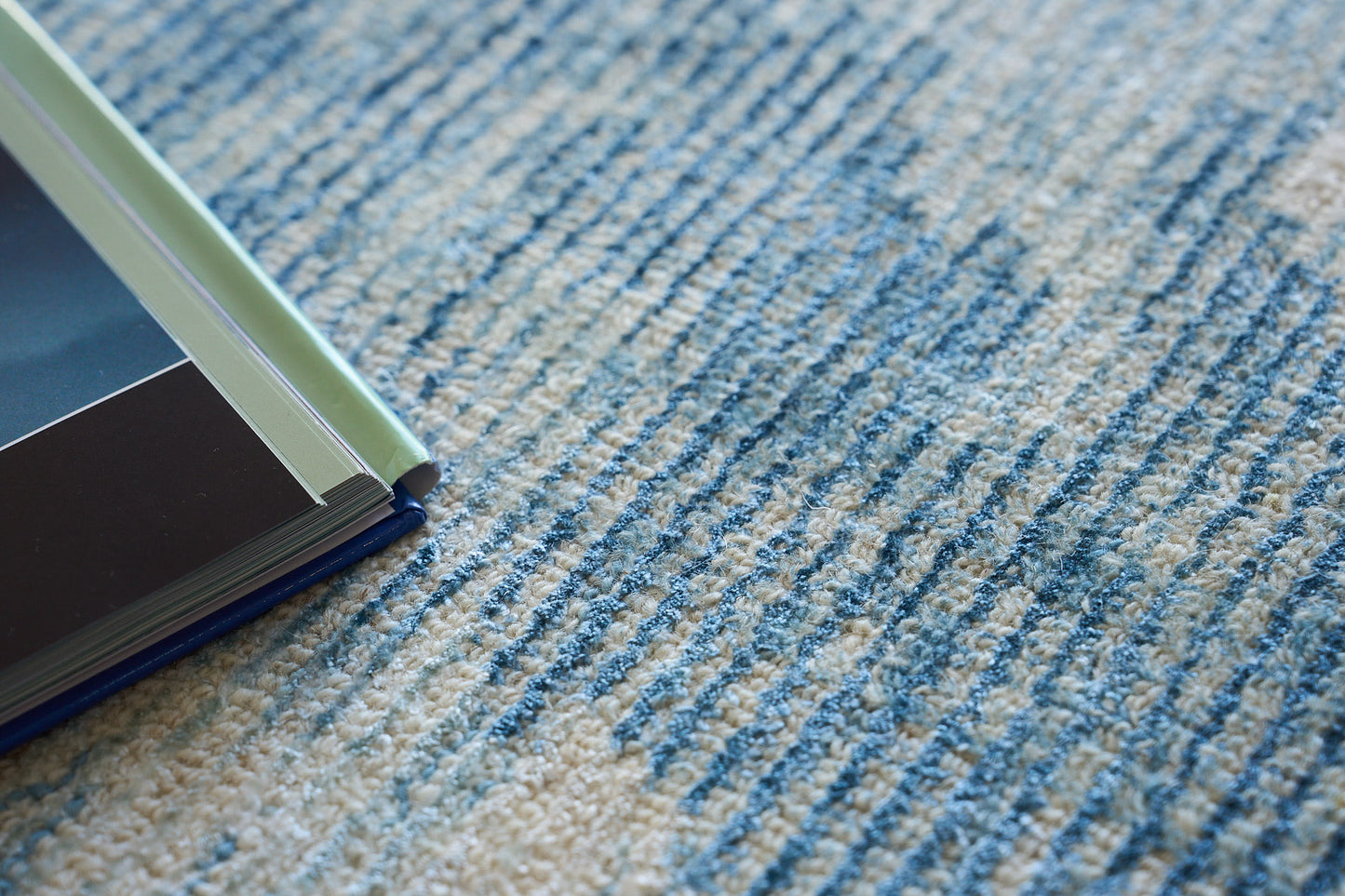 Blue patterned rug with a stack of color swatch books featuring mint green, gray, and navy covers.