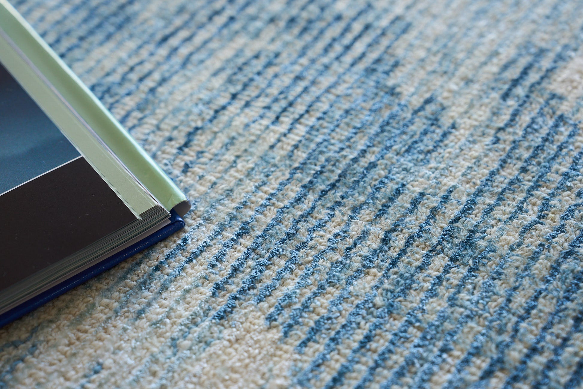 Blue patterned rug with a stack of color swatch books featuring mint green, gray, and navy covers.