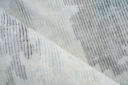 Close-up of a soft gray-blue striped woven rug with textured pile and subtle variegated threads.