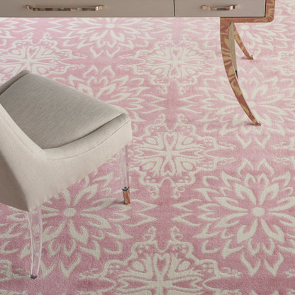 Soft pink rug with white floral medallion pattern; light gray upholstered chair with metal legs beside a modern desk.