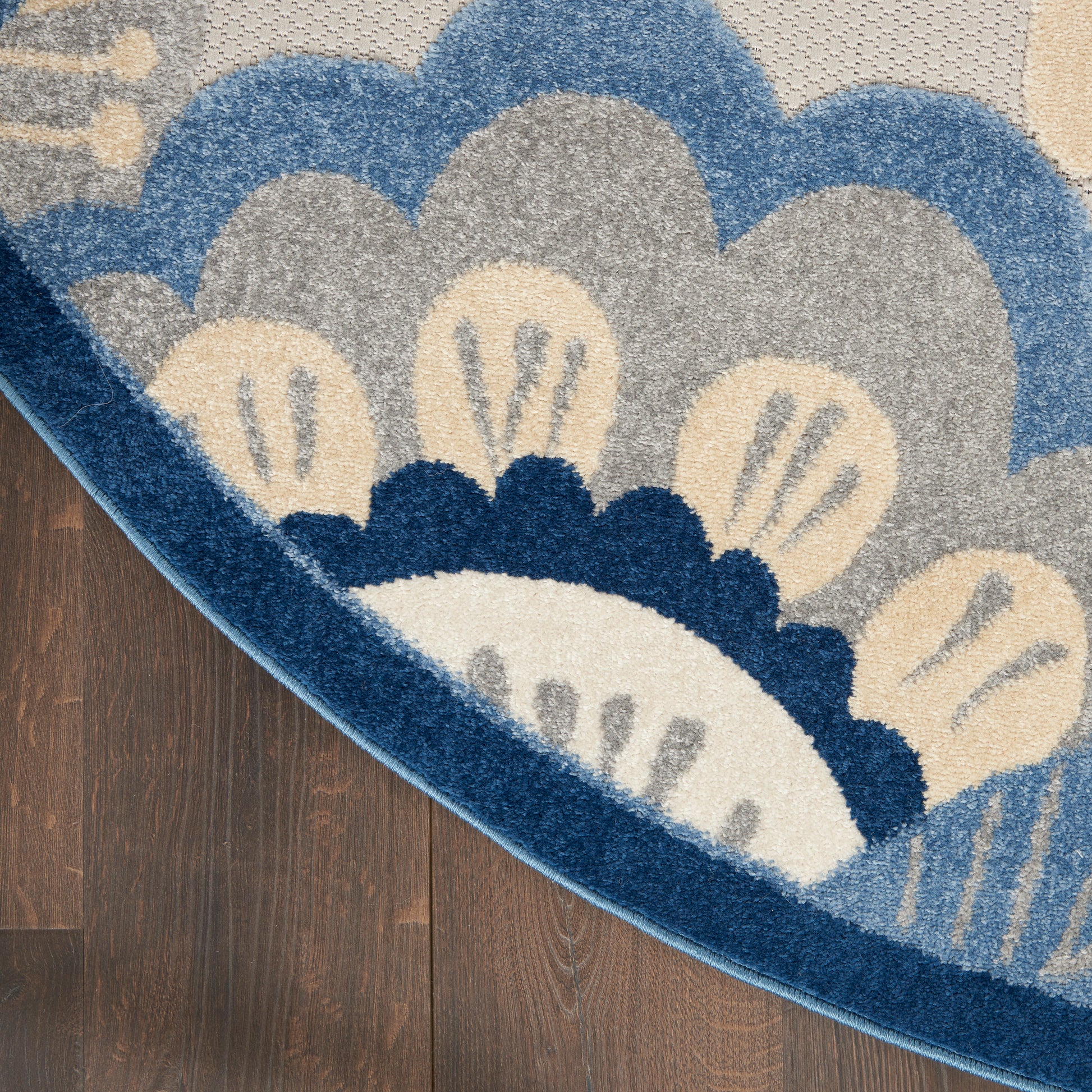 Round blue floral area rug with cream, gray and navy petals on a dark wood floor.